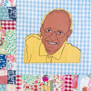 Ben Ali smiling while wearing glasses and a yellow shirt.